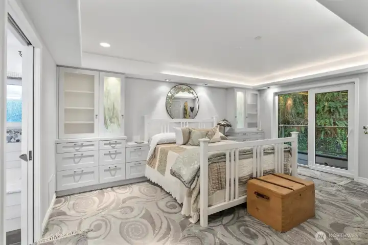 Another view of the primary suite highlights the beautifully crafted built-ins and access to a private view deck. To the left, you’ll find the entry to the en-suite full bath, completing this tranquil and well-appointed retreat.