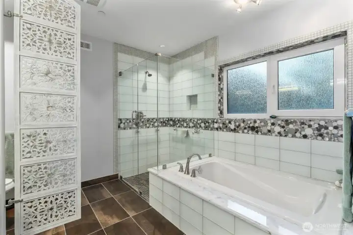 The updated primary bath showcases a sleek, glass-enclosed shower with modern, refined finishes, paired with a deep soaking tub designed for relaxation. Thoughtfully styled and elegantly appointed, the space offers a spa-like atmosphere—perfect for unwinding at the end of the day in comfort and luxury.