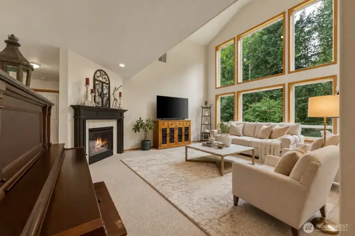 A breathtaking wall of soaring windows floods the great room with natural light while showcasing tranquil views of the surrounding evergreens, creating a stunning connection to the outdoors. Vaulted ceilings, warm wood trim, and a beautiful fireplace add timeless character and warmth, while the open-concept design flows seamlessly into the dining area and kitchen—perfect for both everyday living and effortless entertaining. Newly installed plush carpeting with premium moisture-resistant memory foam-style padding provides exceptional comfort underfoot, enhancing the inviting atmosphere. Thoughtfully designed gathering spaces and a dramatic upper-level overlook make this spectacular living area the true heart of the home. A breathtaking wall of soaring windows floods the great room with natural light while showcasing tranquil views of the surrounding evergreens, creating a stunning connection to the outdoors. Vaulted ceilings, warm wood trim, and a beautiful fireplace add timeless character and warmth, while the open-concept design flows seamlessly into the dining area and kitchen—perfect for both everyday living and effortless entertaining. Newly installed plush carpeting with premium moisture-resistant memory foam-style padding provides exceptional comfort underfoot, enhancing the inviting atmosphere. Thoughtfully designed gathering spaces and a dramatic upper-level overlook make this spectacular living area the true heart of the home.