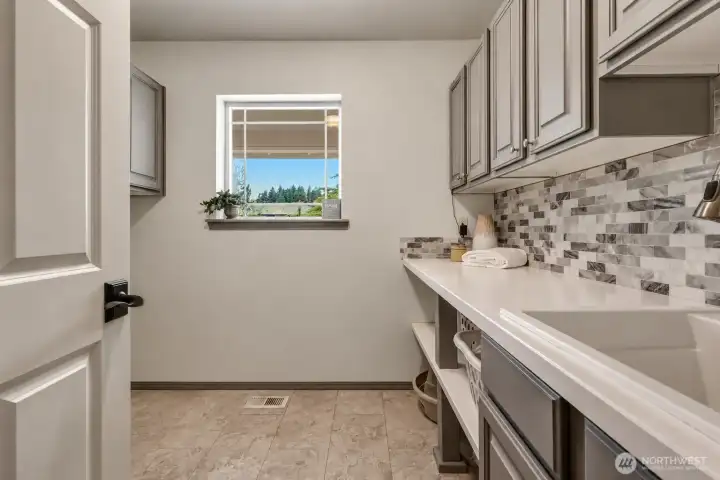 A beautifully remodeled laundry room adds everyday convenience with Quartz Countertop, generous cabinetry, a utility sink, tile flooring, and stylish backsplash detail. The counter space is ideal for folding, organizing, or extra storage, while the window brings in natural light and peaceful outdoor views. Thoughtfully designed with both function and style, this space makes daily routines feel easy and organized. A beautifully remodeled laundry room adds everyday convenience with Quartz Countertop, generous cabinetry, a utility sink, tile flooring, and stylish backsplash detail. The counter space is ideal for folding, organizing, or extra storage, while the window brings in natural light and peaceful outdoor views. Thoughtfully designed with both function and style, this space makes daily routines feel easy and organized.