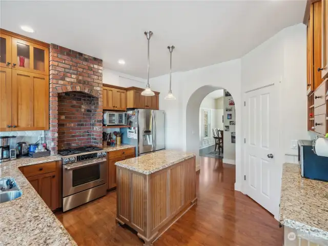 Arched doorway leads to the fantastic kitchen with granite counters, island for prep space, and beautiful wood cabinetry with custom touches. Generous sized pantry provides additional storage.