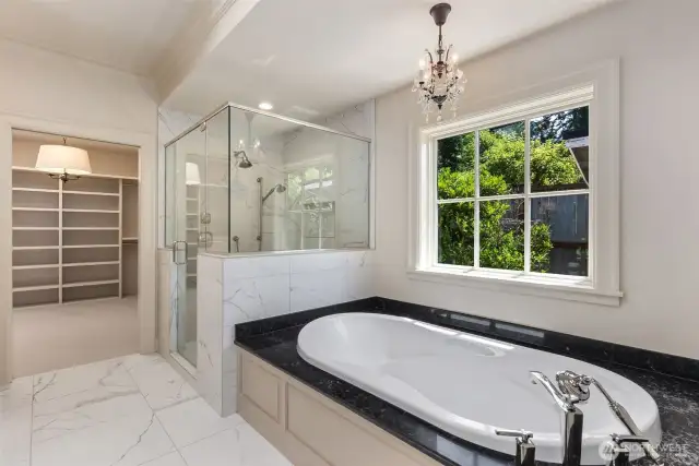 Lovely soaking tub and primary shower leading directly to the expansive walk-in closet.