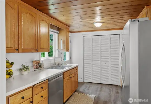 Galley style kitchen with stainless steel appliances, laundry closet, backyard facing sink window and door to backyard patio.