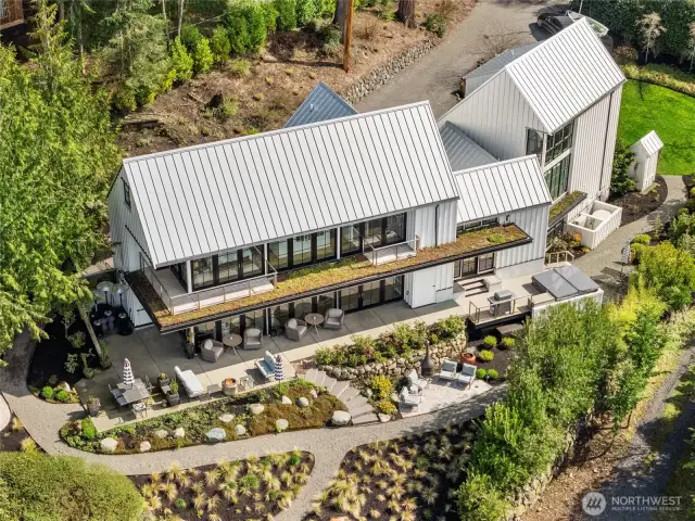 TTwo serene primary suites rest on either side of a light-filled breezeway, offering comfort and privacy. Curated gardens and lawn blend seamlessly with shoreline ecology, while a sleek metal roof and living decks elevate the home’s coastal design.