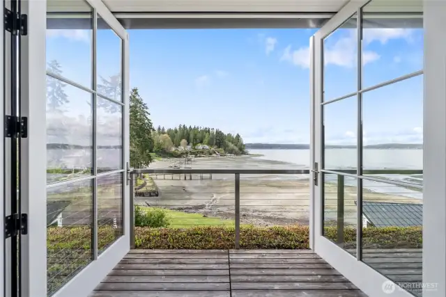 View to the water through the tall French doors and across the Green deck. A well-organized primary closet with coffee bar, complete with counter, sink, filtered-water refrigerator, and washer/dryer.