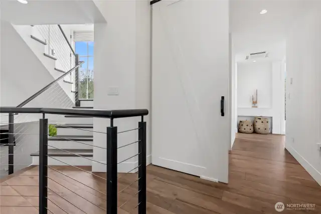 Stairs rise to the media room and second primary suite, where a barn-style door creates a private wing separate from the main home.