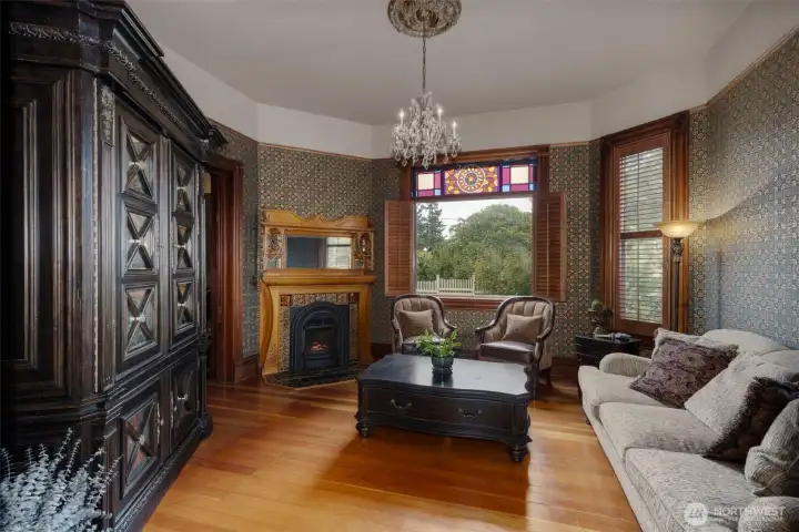 To the right of the Foyer is the main living room. A modern propane insert fireplace against the east wall makes for an easy warm glow on cool evenings while the classic large glass windows with stained glass accents open up to what appear to be your private arboretum. Custom Hunter Douglas wood shutters provide a period appropriate solution to light management. The high ceilings give the great room and even greater feel and volume. (The space would be the ideal location for a high end listening room)