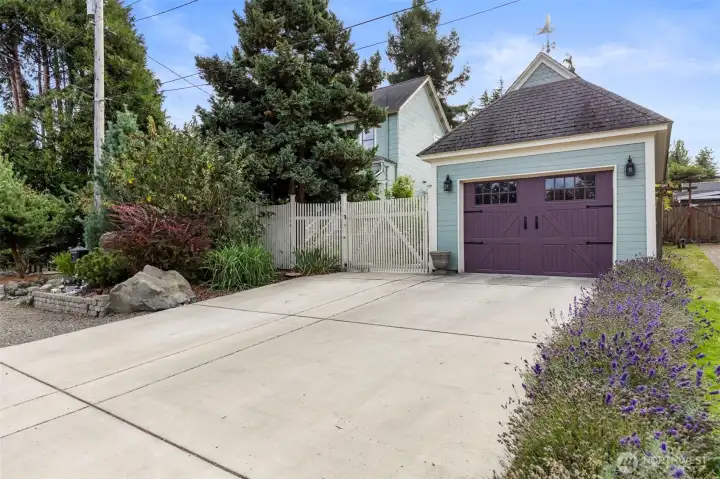 Moving outside, a view of the outdoor parking area and detached garage and gate entry.  The Garage looks like a classic carriage house and is the most visible part of the home from the street.