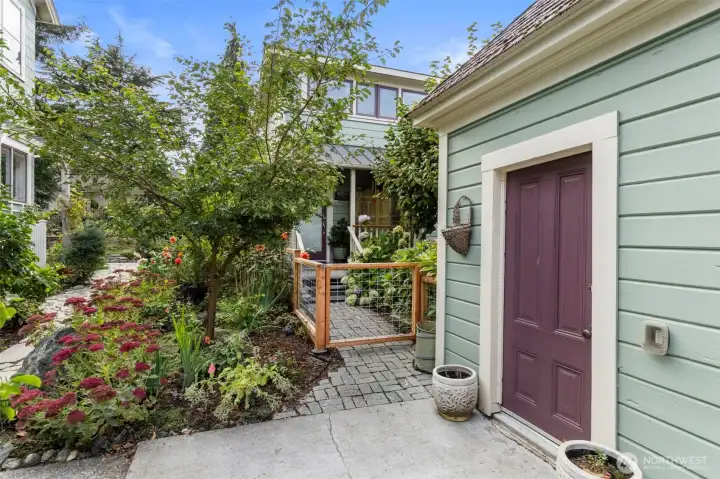 The side entry to the garage is within the fenced property. Just to the right of the door is the gate to the ADU with it's private porch and garden area. The privacy of this ADU is quite remarkable considering it's proximity to the home.