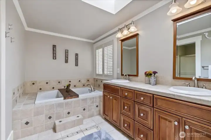 Primary bathroom with full soaking tub, skylight and dual vanity.  Shower is located opposite of the sinks.