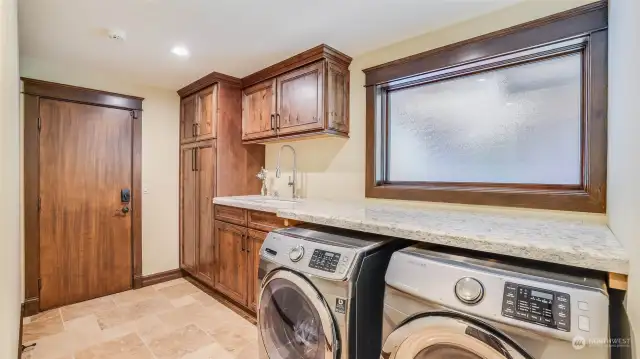 Utility room with custom cabinetry, pull out drawers, quartz counter, Farmhouse sink, privacy glass and travertine floors.