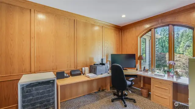 Handsome den is wrapped in natural wood judges paneling with built-in cabinetry and shelves.