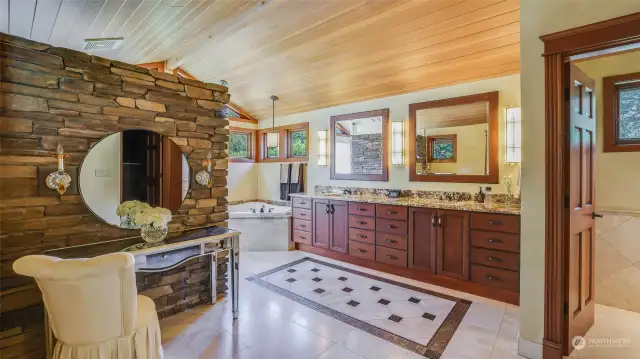 Primary bath features clear cedar vaulted ceiling, walk-in shower with stone walls and dual shower heads, granite counter with dual vanities and radiant travertine floors.