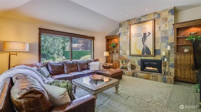 Inviting family room features floor-to-ceiling slate-faced gas fireplace flanked by handsome built-in cabinetry and glass shelves lit from the top