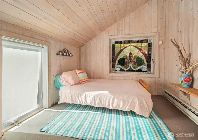 One of three bedrooms on the upper level with western window and north-facing stained glass window.