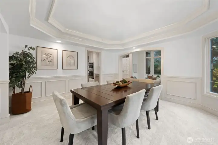 Well-appointed dining room with tray ceiling, detailed wainscoting, and generous windows, conveniently located just steps from the kitchen—ideal for effortless serving and entertaining.
