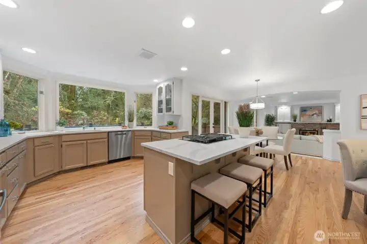 Completely remodeled kitchen featuring quartz countertops, a generous center island with seating, updated fixtures, and beautifully refinished hardwood floors—designed for both function and style.