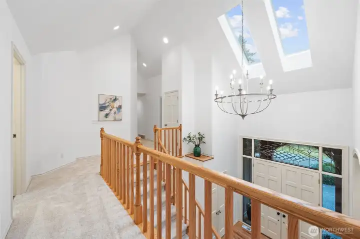 Upper-level landing featuring vaulted ceilings—creating an open, airy passage leading to the Primary Bedroom, Bedroom Two, and the recreation room.