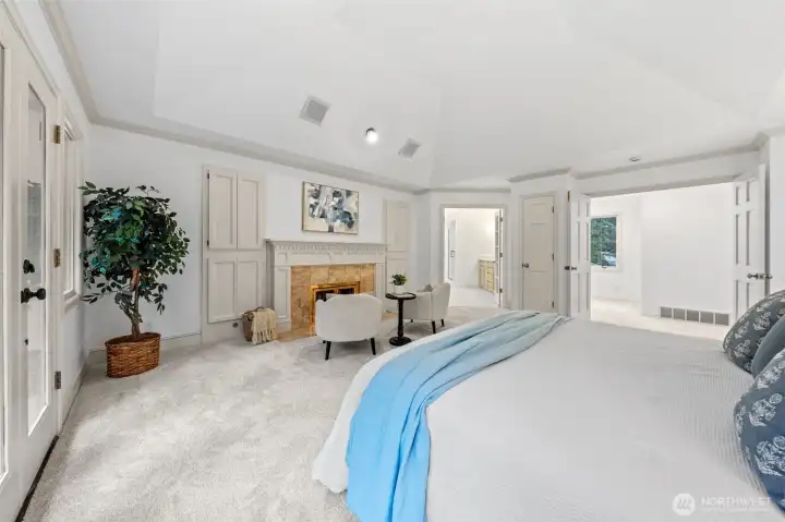 A second perspective highlights the suite’s warm and inviting layout, featuring a gas fireplace, elegant architectural details, and seamless flow to the primary bath. The vaulted ceilings enhance the airy feel, creating a true retreat-like atmosphere.