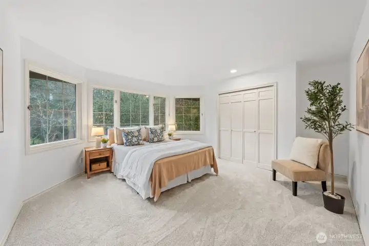 Bedroom Three features new carpet, fresh paint, and ample closet space, highlighted by a large window with peaceful greenery views and beautifully detailed wood-wrapped window trim.