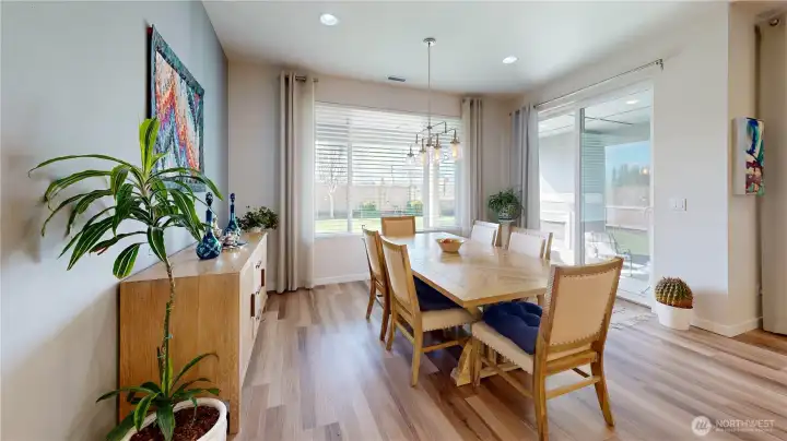 Light-filled dining area with large windows, warm LVP flooring, and access to the backyard oasis.