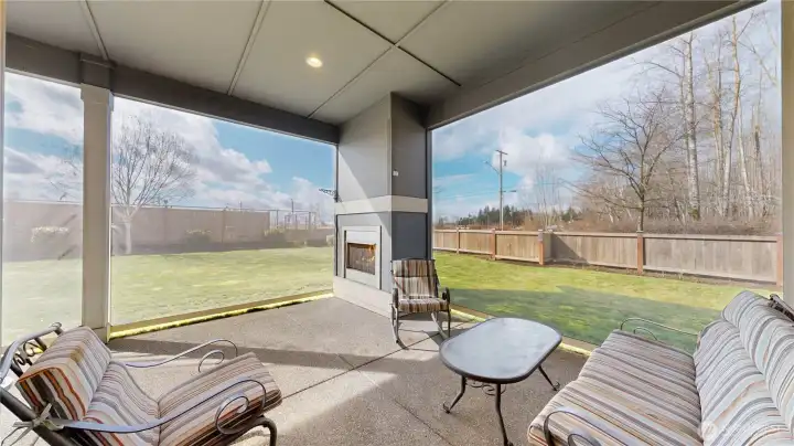 Covered patio with privacy screens, outdoor fireplace, and mountain view backdrop.