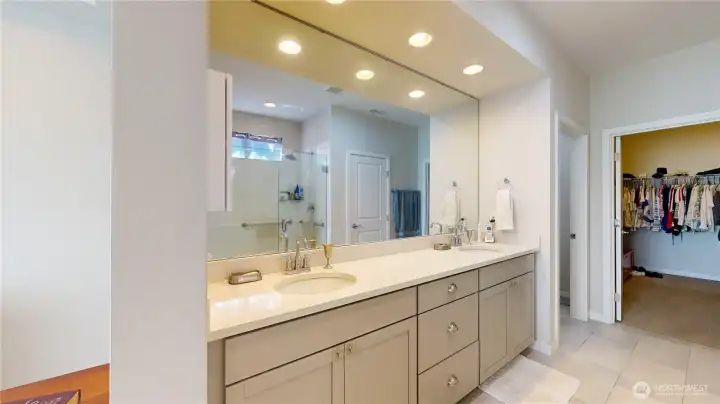Primary bath with dual-sink vanity, glass-enclosed shower, and walk-in closet