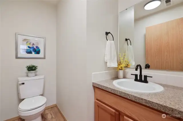 Behind the dining room, just off of the garage door entrance, you'll find a convenient powder room, with a stylish black matte faucet fixture, updated lighting and BRAND new toilet!