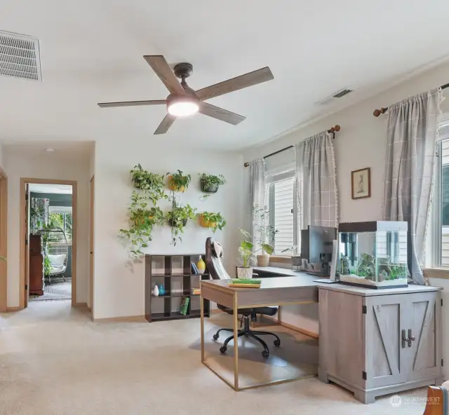 At the top of the stairs, the space opens up to a large bonus family room with two windows just right for a home office under a comforting contemporary ceiling fan.