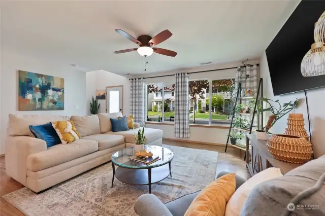 Inside, the generously sized living room has a wall of windows overlooking the front porch, and this angle also shows the entry foyer area as well. A ceiling fan keeps everyone comfortable year round, as well as the NEW air conditioning unit just installed last year!