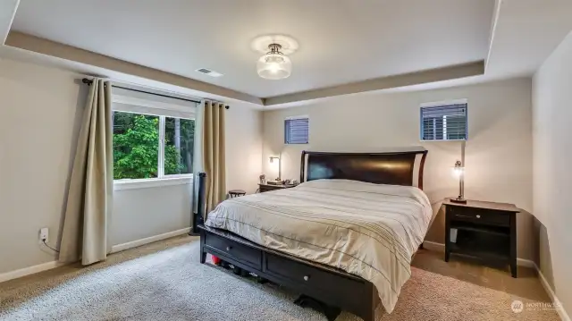 The primary bedroom is divided into two separate spaces, with continued tray ceiling and inviting warm colors.