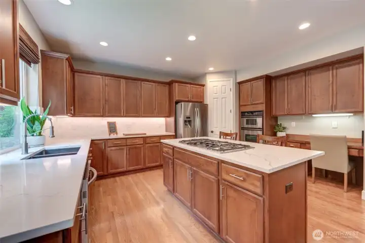 “Spacious kitchen with new quartz counters, designer tile backsplash, gas cooktop, island, and walk-in pantry—open to the family room for easy entertaining.”