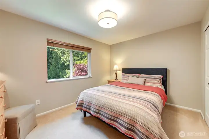 “Comfortable third bedroom with natural light and a built-in closet organizer for easy storage.”