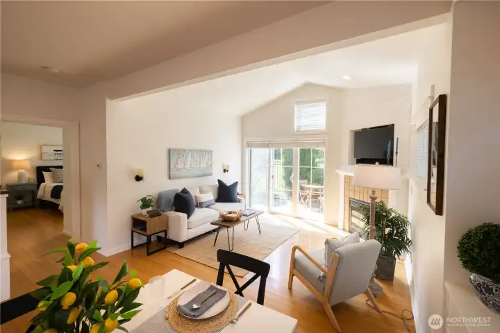 Open floor plan with a nice dining area with built-ins, and a spacious light filled vaulted ceiling living room with a propane fireplace and glass doors leading to the fenced and gated back yard and patio and a beautiful green common area beyond.