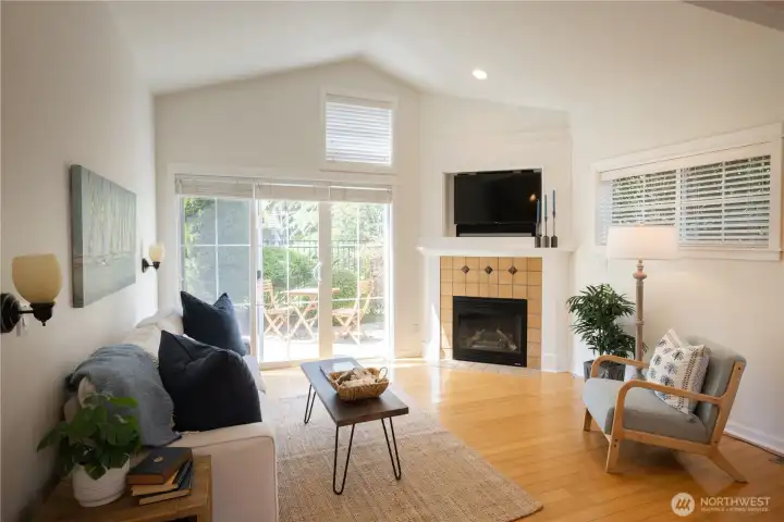 Lovely light filled vaulted ceiling living room with a cozy propane fireplace, lots of windows and a glass doors leading to the sunny patio and gardens, plus the very nice common area green space through the fenced and gated back yard.