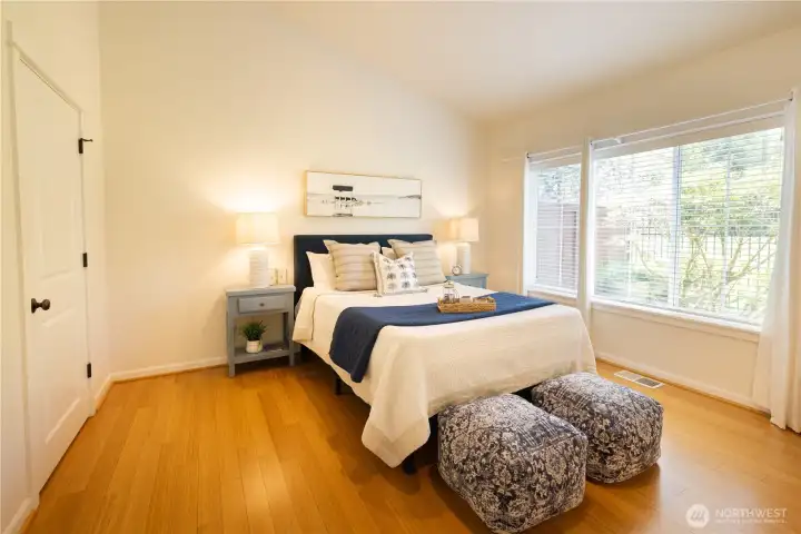 Primary main floor bedroom suite with vaulted ceilings, beautiful flooring, a walk-in closet and an en-suite bathroom.