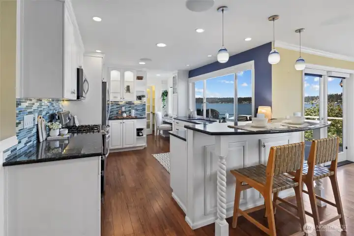 The chef’s kitchen is beautifully appointed with stainless steel appliances, double ovens, walk-in pantry, breakfast nook, and adjoining dining area opening to an entertaining deck overlooking the water.