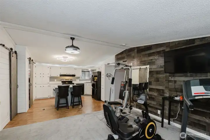 Family room opposite the kitchen is currently being used as a home gym. Complimentary custom wood wall matches the one in the living room. Family room opposite the kitchen is currently being used as a home gym. Complimentary custom wood wall matches the one in the living room.