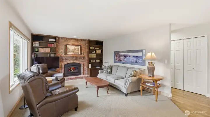 The family room features a gas log fireplace with a real brick surround and built-in cabinets.  The large window lets light flow into the room.