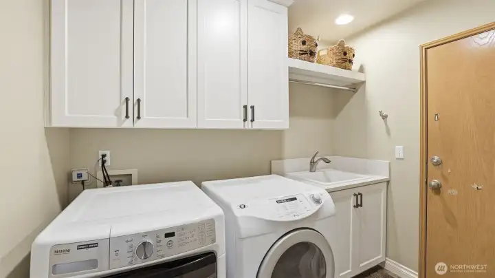 The utility room has a deep sink, built-in cabinets and the washer/dryer remain.