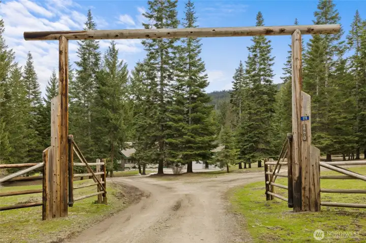 Welcoming over & under log entrance! The property is partially fenced, & features four rail log fencing out front as well as a secondary gated entry.
