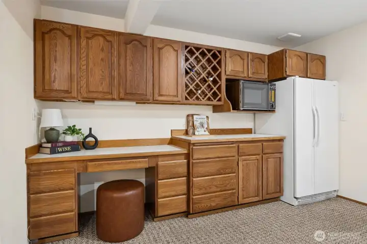 Lower level features built-in cabinetry with a wine rack, microwave and refrigerator.