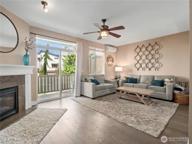 This inviting space features rich hardwood floors, a cozy gas fireplace with a classic white mantel, and large sliding glass doors that flood the room with natural light while offering access to a private balcony.