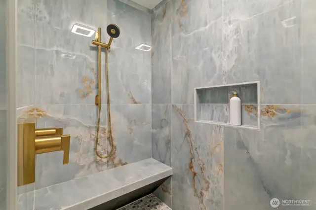 Walk-in shower with dual shower heads and heated bench seat.