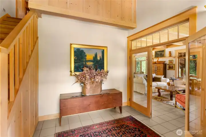 Welcoming main entry with tile floors and warm wood finishes, featuring a staircase to the second level and an inviting transition into the light-filled living spaces