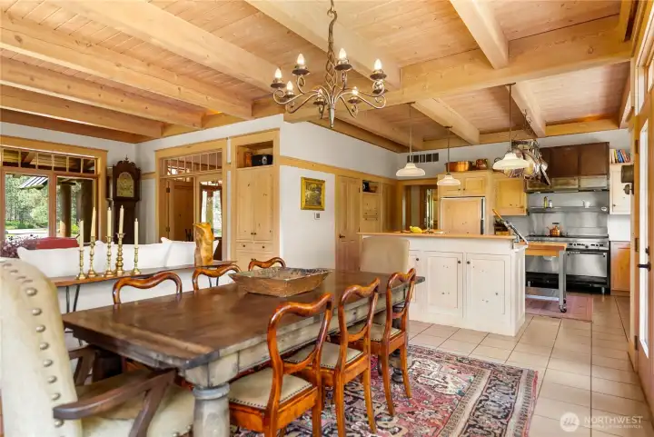 Warm and inviting dining area seamlessly connected to the kitchen, featuring rich wood finishes, walk-in pantry, abundant built-in cabinetry, and an oversized island with seating—perfect for gathering and entertaining