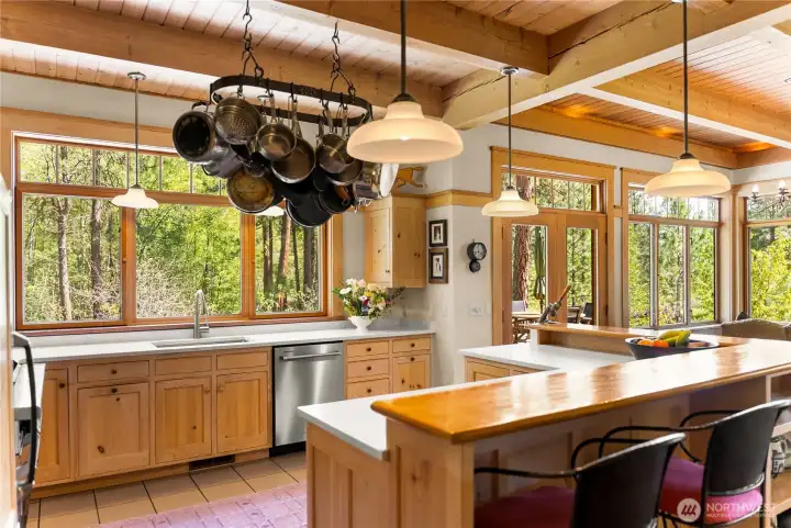 Bright, beautifully appointed kitchen with granite countertops, custom wood cabinetry, and a central island with seating—framed by expansive windows