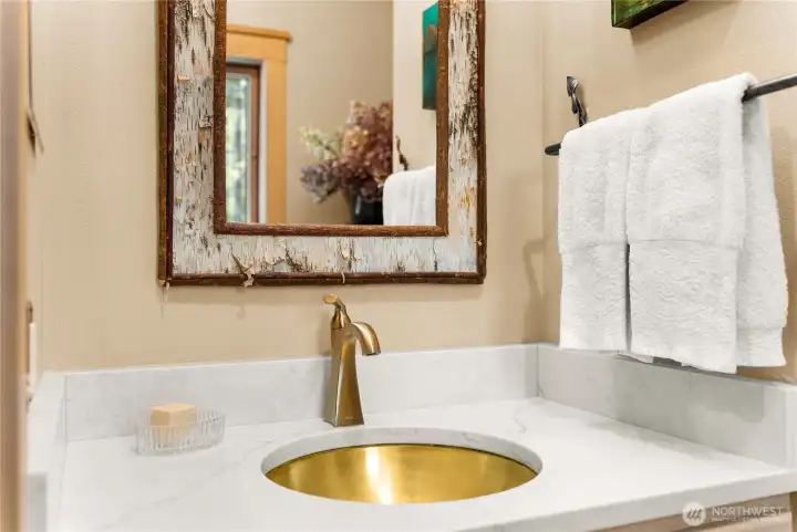 Main floor powder bath with stylish finishes, featuring a quartz countertop, vessel sink, and designer fixtures—plumbed for easy conversion to a full bath if desired