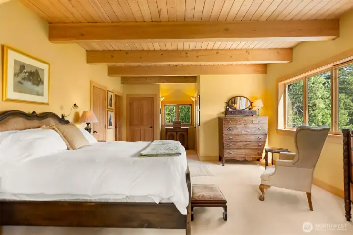 Spacious primary suite offering a spacious, warm wood ceilings, complemented by dual walk-in closets for exceptional storage and everyday ease