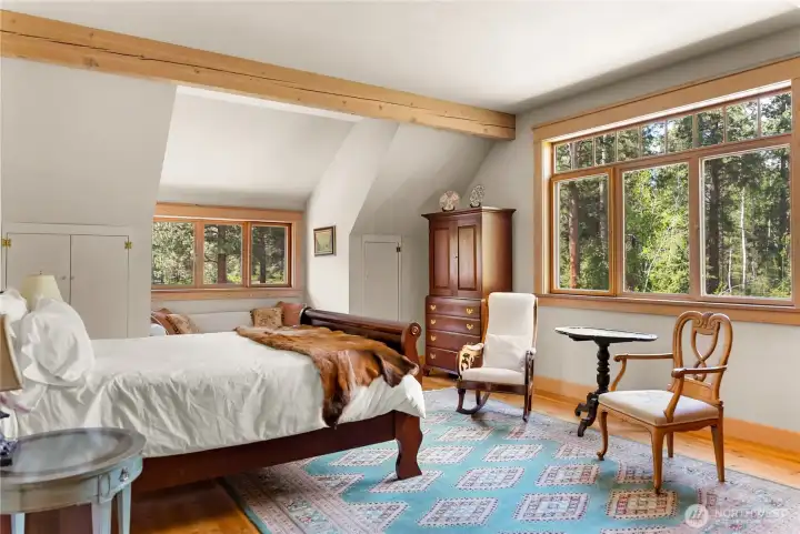 Second upstairs ensuite featuring a spacious, light-filled bedroom with warm wood accents, large windows, and a private bath—comfortable and inviting for guests or family